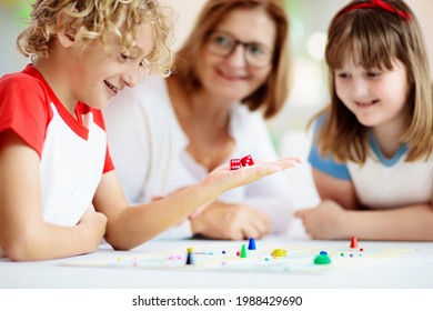 Family Playing Board Game At Home. Kids Play Strategic Game. Little Boy Throwing Dice. Fun Indoor Activity For Summer Vacation. Siblings Bond. Educational Toys. Friends Enjoy Game Night.