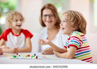 Family Playing Board Game At Home. Kids Play Strategic Game. Little Boy Throwing Dice. Fun Indoor Activity For Summer Vacation. Siblings Bond. Educational Toys. Friends Enjoy Game Night.