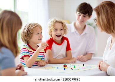 Family playing board game at home. Kids play strategic game. Little boy throwing dice. Fun indoor activity for summer vacation. Siblings bond. Educational toys. Friends enjoy game night.