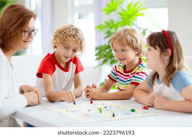 Family playing board game at home. Kids play strategic game. Little boy throwing dice. Fun indoor activity for summer vacation. Siblings bond. Educational toys. Friends enjoy game night. - Powered by Shutterstock