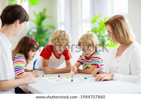 Family playing board game at home. Kids play strategic game. Little boy throwing dice. Fun indoor activity for summer vacation. Siblings bond. Educational toys. Friends enjoy game night.