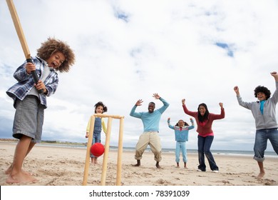 Family Playing Cricket On Beach