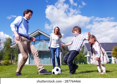 Family Playing Football In Front Of Their House