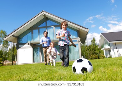 Family Playing Football In Front Of Their House