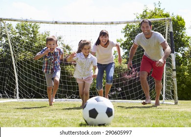 Family Playing Football In Garden Together