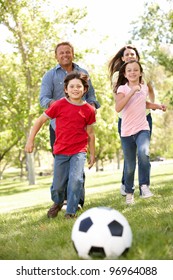 Family Playing Football In Park