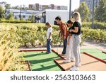 family playing mini golf on a cruise liner. Child having fun with active leisure on vacations.