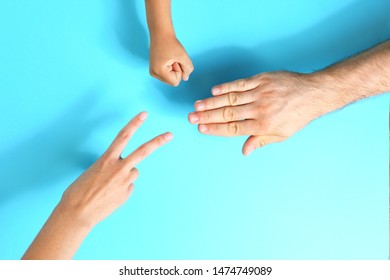 Family Playing Rock, Paper And Scissors On Blue Background, Closeup