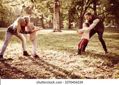 Family playing with rope in park.