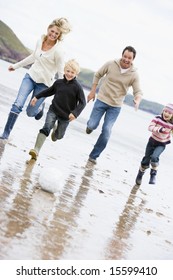 Family Playing Soccer At Beach Smiling