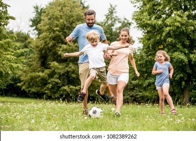 Family Playing Soccer In The Park And Having Fun