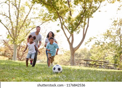 Family Playing Soccer In Park Together