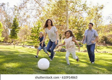 Family Playing Soccer In Park Together