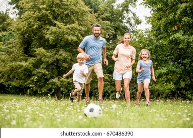 Family playing soccer in summer with their children - Shutterstock ID 670486390