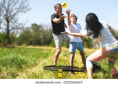 family playing spikeball in nature. parents with children play active games on summer holidays. Spikeball is a miniature analogue of volleyball. - Powered by Shutterstock