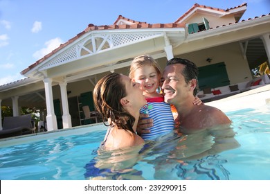 Family Playing In Swimming Pool Of Private Villa