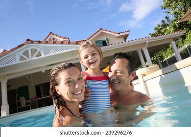 Family Playing In Swimming Pool Of Private Villa