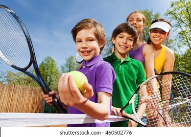 Family playing tennis holding rackets and ball