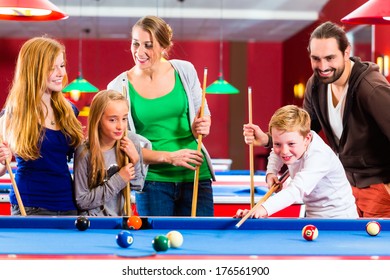 Family Playing Together Billiard With Queue And Balls On Pool Table 