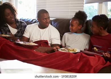 Family With Poor Diet Sitting On Sofa Eating Meal