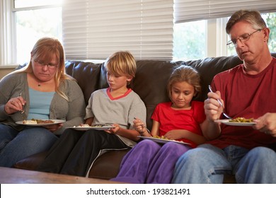 Family With Poor Diet Sitting On Sofa Eating Meal