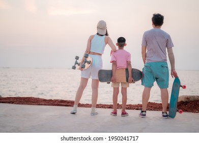 Family portrait, beach vacation, parents and children resting from skating, surfing, standing smiling happily. - Powered by Shutterstock