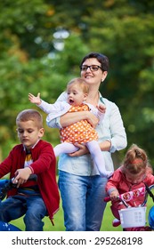 Family Portrait Outdoor In Park. Modern Mom With Kids. Child Learning To Ride Bike