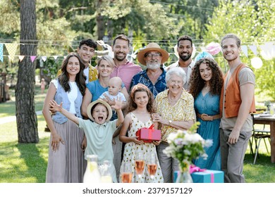 Family portrait at outdoor summer garden party. Family and friends standing, posing for a group photo. Multigenerational family. - Powered by Shutterstock