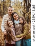 Family portrait of parents with two daughter, standing in the middle of forest.