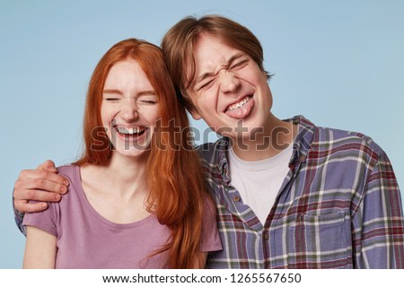 family portrait of young cheerful funny joyful couple, play ape, smile and feels happy. Indoor shot of young male with braces hugs his girlfriend wich smiles broadly