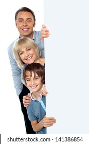 Family Posing From Behind Blank White Ad Board