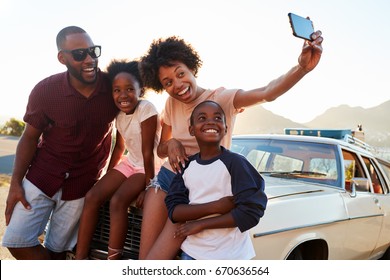 Family Posing For Selfie Next To Car Packed For Road Trip