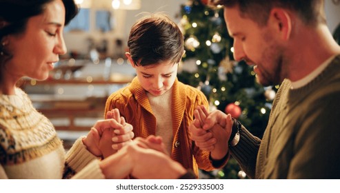 Family, prayer and holding hands in house for Christmas, solidarity and gratitude with spiritual connection. Parents, boy and worship in living room for thanks, faith and vacation as Christian people - Powered by Shutterstock