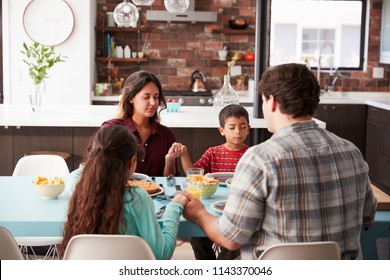 Family Praying Before Meal Around Table At Home