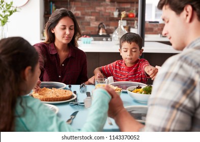 Family Praying Before Meal Around Table At Home