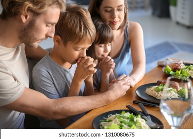 Family Praying Before Meal At Home