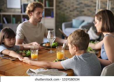 Family Praying Before Meal At Home