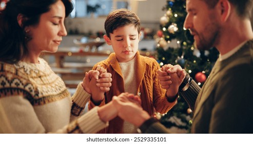 Family, praying and holding hands in home for Christmas, solidarity and gratitude with spiritual connection. Parents, boy and worship in living room for thanks, faith and vacation as Christian people - Powered by Shutterstock