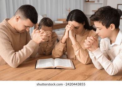 Family praying together with Holy Bible on table at home - Powered by Shutterstock