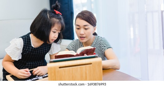 Family Praying And Worship To GOD With Church Online Sunday Service.Live Church With Bible.Mom And Daughter Reading Holy Bible At Home.Home Church.Quarantine From Covid-19 Coronavirus Pandemic