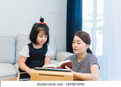 Family Praying And Worship To GOD With Church Online Sunday Service.Live Church With Bible.Mom And Daughter Reading Holy Bible At Home.Home Church.Quarantine From Covid-19 Coronavirus Pandemic