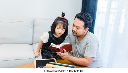 Family praying and worship to GOD with church online sunday service.Live Church with wisdom of GOD in Bible.Father and kid reading on holy bible at home.Quarantine from Covid-19 Coronavirus pandemic