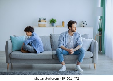 Family problems concept. Annoyed father sitting back to back with son on sofa, ignoring each other after argue. Stubborn dad and boy don't looking or speaking after conflict