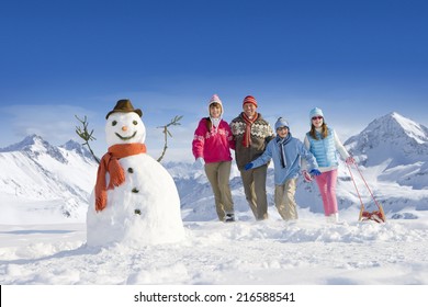 Family Puling Sled Towards Snowman