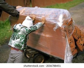 A Family Pushing Second Hand Sofa Loaded On A Trolley, Outdoor High Resolution Image