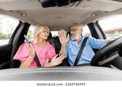 Family quarrel In auto. Angry senior couple arguing and shouting at each other in car while driving in automobile. Emotional elderly retired spouses having conflict, discussing road, shot from inside - Powered by Shutterstock