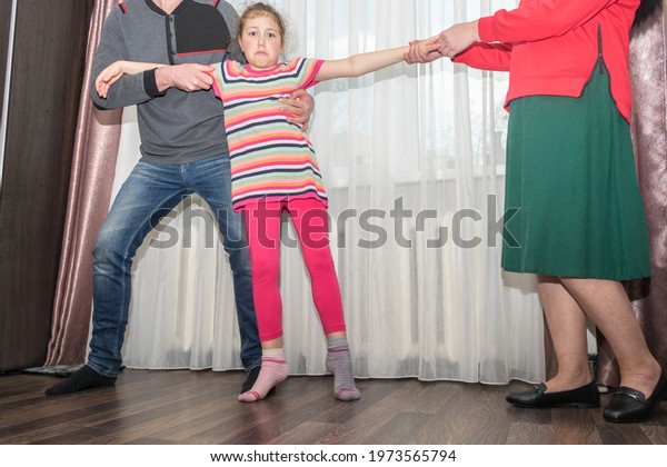Family quarrel. A man and a woman are trying to\
share their daughter. The father takes the child from the mother.\
Family conflict concept.
