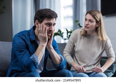 Family quarrel, woman quarrels and yells at the loser's husband, couple at home sitting in the living room on the couch