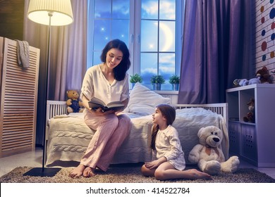 Family Reading Bedtime. Pretty Young Mother Reading A Book To Her Daughter.