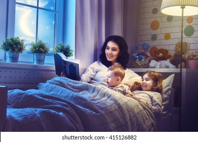 Family Reading Bedtime. Pretty Young Mother Reading A Book To Her Daughters.